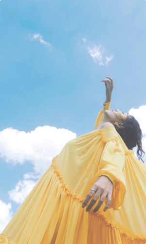 A women in a yellow dress looking up to the sky